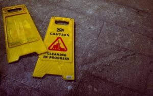 : A yellow caution sign on a floor stating cleaning in progress.