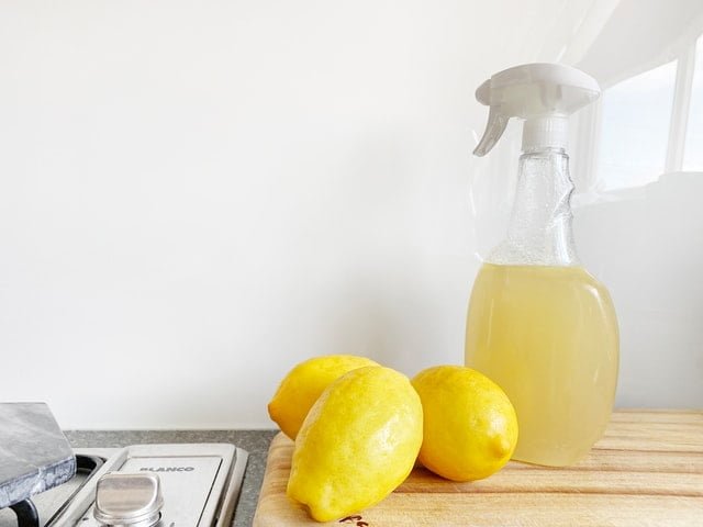 Three lemons and lemon spry on the kitchen counter.