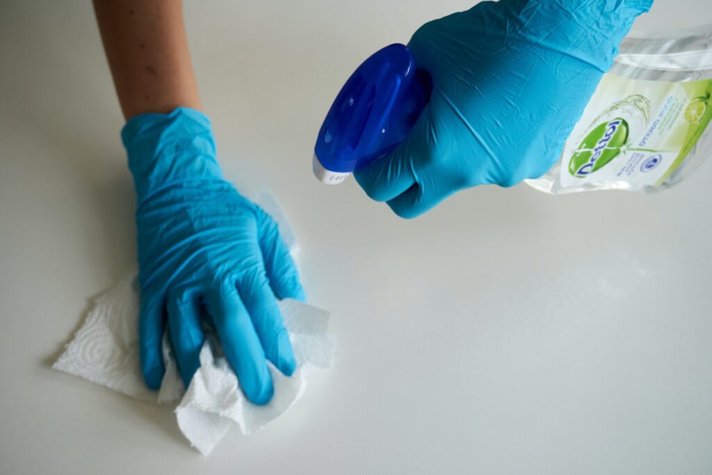 A person wearing blue gloves, cleaning a white surface