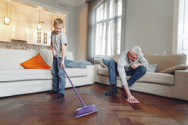 a man and a boy spring cleaning the floor with a broom and a cloth