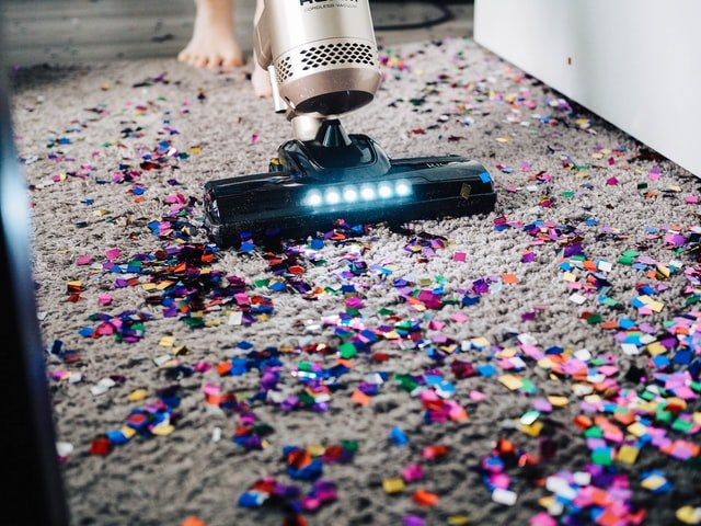 A vacuum cleaner cleaning a messy rug.