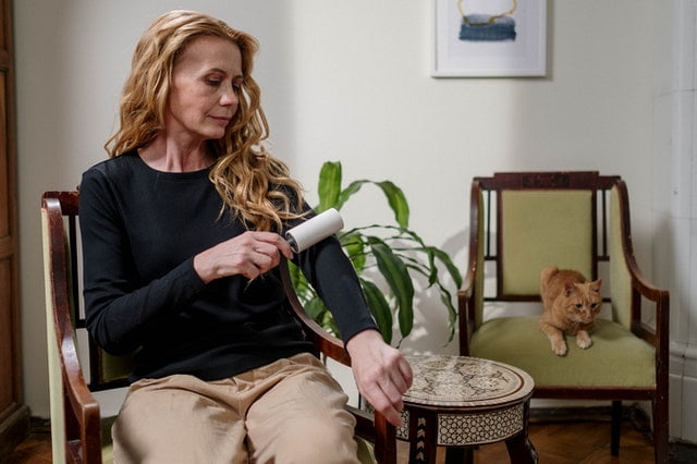 A woman using a lint roller which is one of the excellent cleaning tips for pet owners