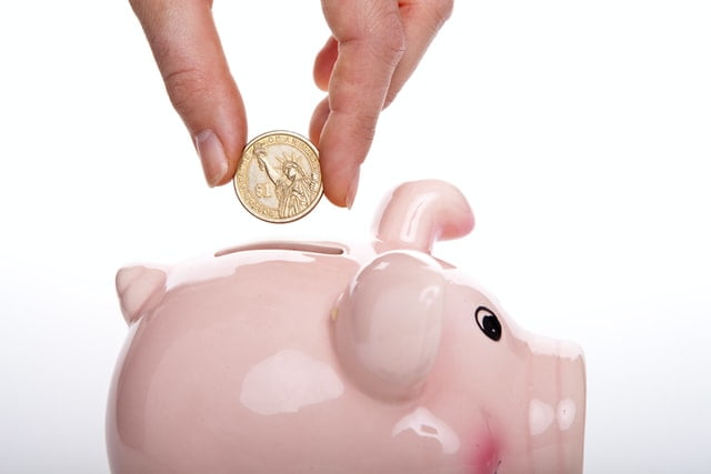 A person putting a coin into a piggy bank