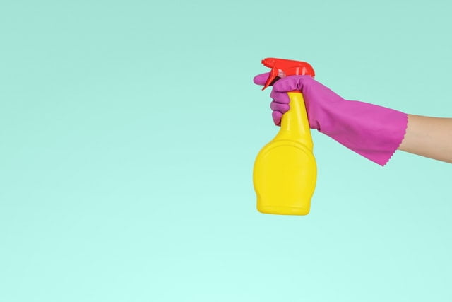 A person holding a yellow plastic spray bottle.