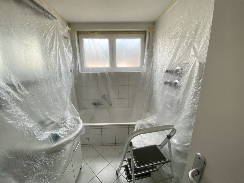 covered bathroom walls with tarp and ladder in preparation for painting. Post construction cleanup