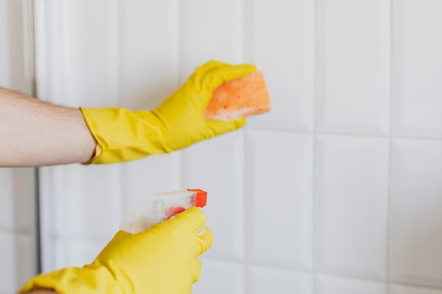 An apartment deep clean professional with gloves and cleaning liquid.