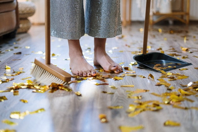 A woman cleaning confetti from the floor.