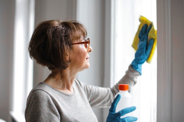 A woman cleaning windows and blinds