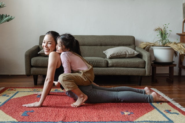 A mother and daughter playing on the carpet