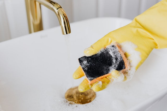 A person holding a sponge over the sink