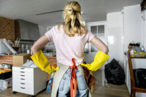 cleaning apartment Woman with gloves and apron with hands on hips