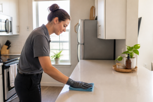 Professional cleaner wipes a decluttered apartment kitchen countertop