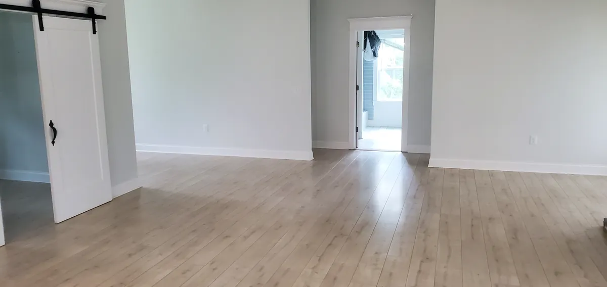 An empty room with wood-look flooring and a sliding barn door.