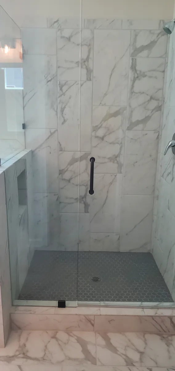 A glass shower enclosure with tiled walls and floor.