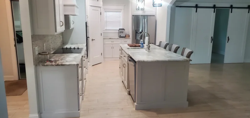Kitchen with white cabinets, stone counters, and an island from Spotlessly Clean’s job-photo collection